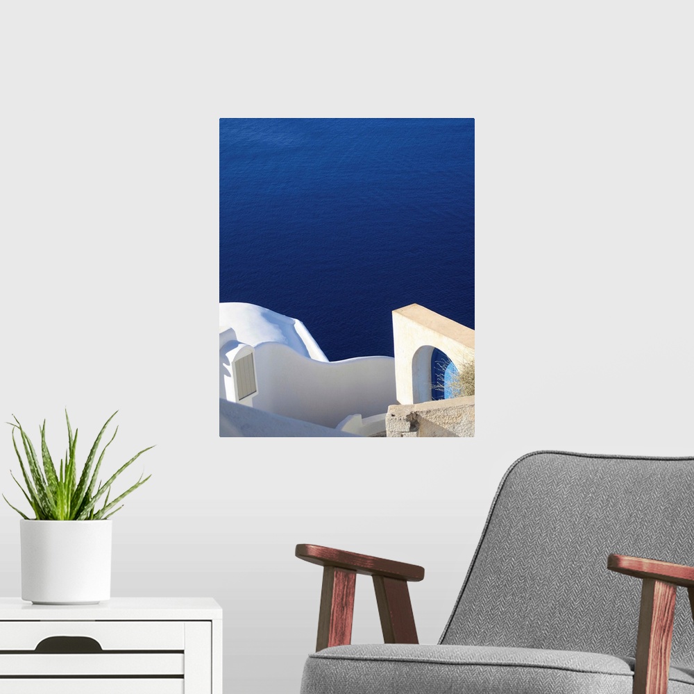 A modern room featuring Landscape photograph of the bright blue water in Santorini.