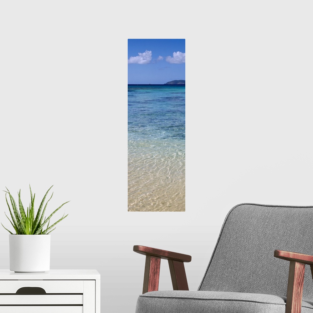 A modern room featuring Tall and narrow canvas print of clear Caribbean ocean water with a mountain in the distance.