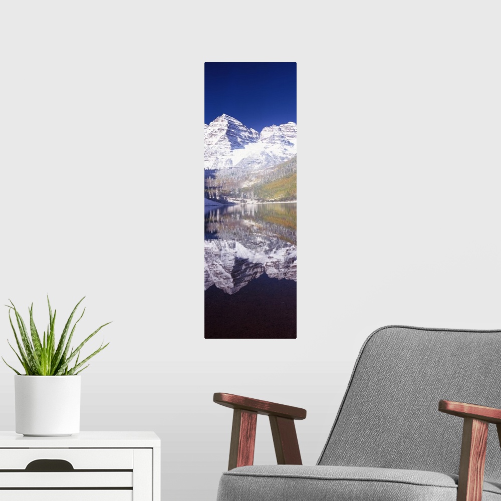 A modern room featuring Vertical panoramic photograph of snow covered mountain that is reflected in the water below.