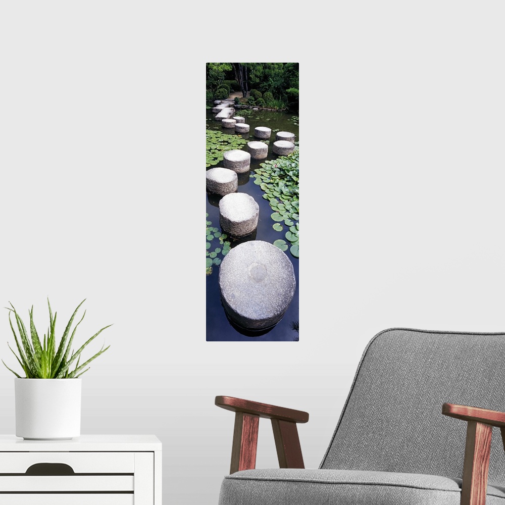 A modern room featuring A tall panoramic piece of large stepping stones that create a path through the water in a shrine ...