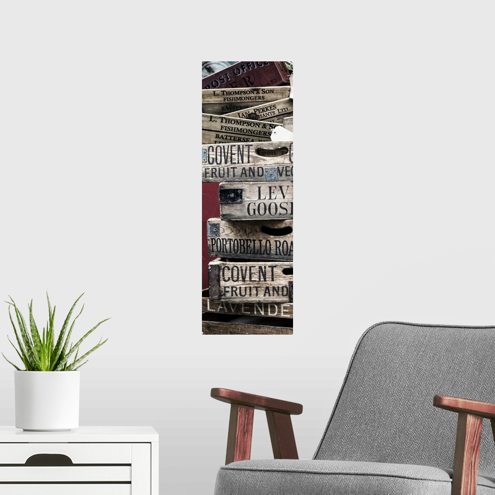 A modern room featuring A stack of weathered wooden crates with names of markets lettered on the sides.