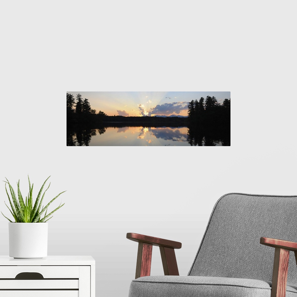 A modern room featuring A photograph of a beautiful sun rising over an idyllic landscape. Being reflected in a lake, whil...