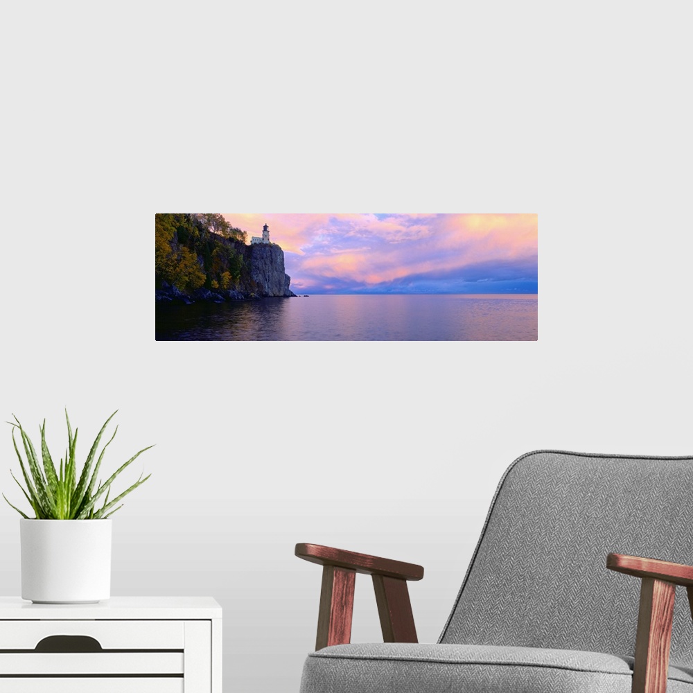 A modern room featuring Panoramic photo print of a lighthouse on top of a cliff overlooking the water at sunset.