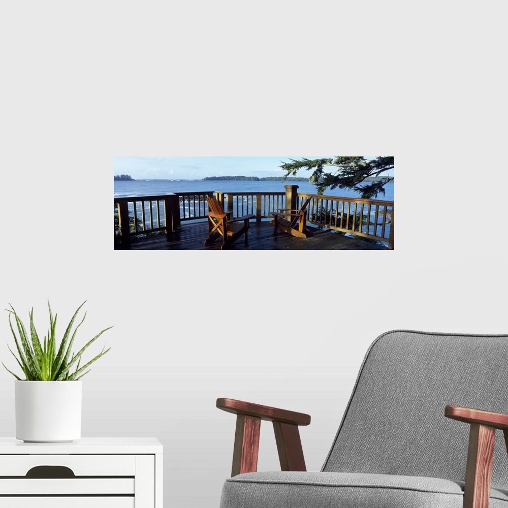 A modern room featuring Two chairs sit on a raised deck overlooking a large body of water.
