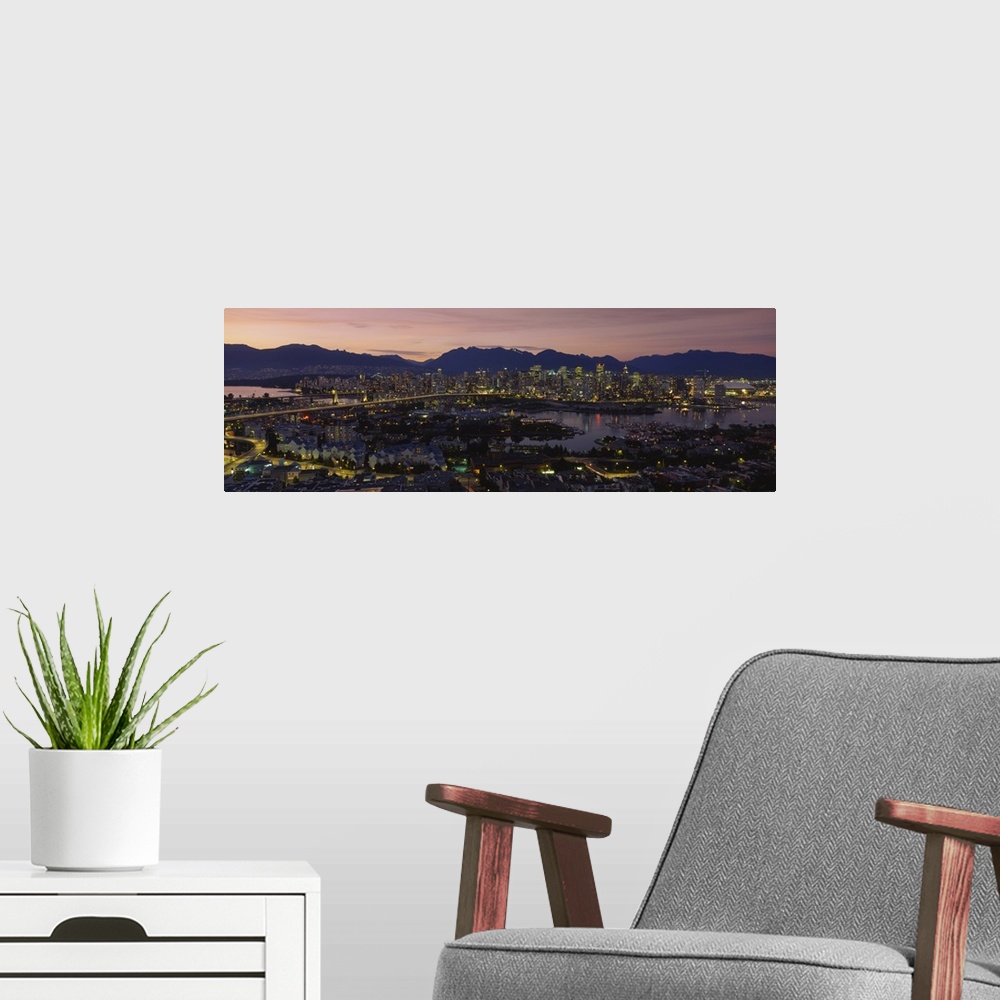 A modern room featuring Panoramic photograph of skyline and waterfront at sunset with buildings lit up and mountain silho...