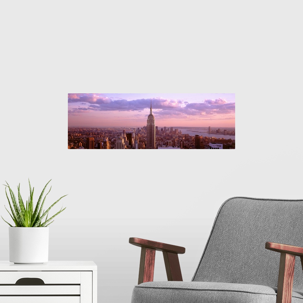 A modern room featuring Aerial panoramic picture of New York City and the top of the Empire State Building in the pink gl...