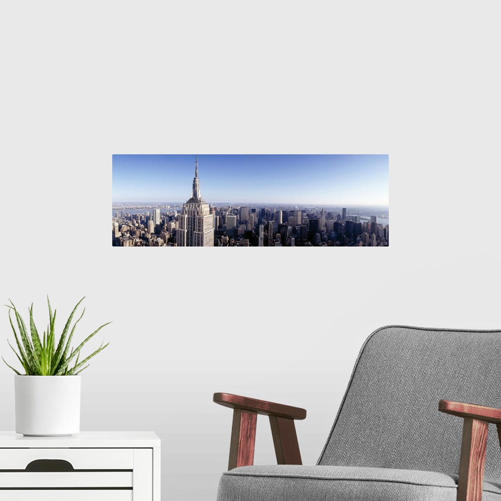 A modern room featuring A high angle photograph of the NYC skyline with the Empire State building in the foreground tower...