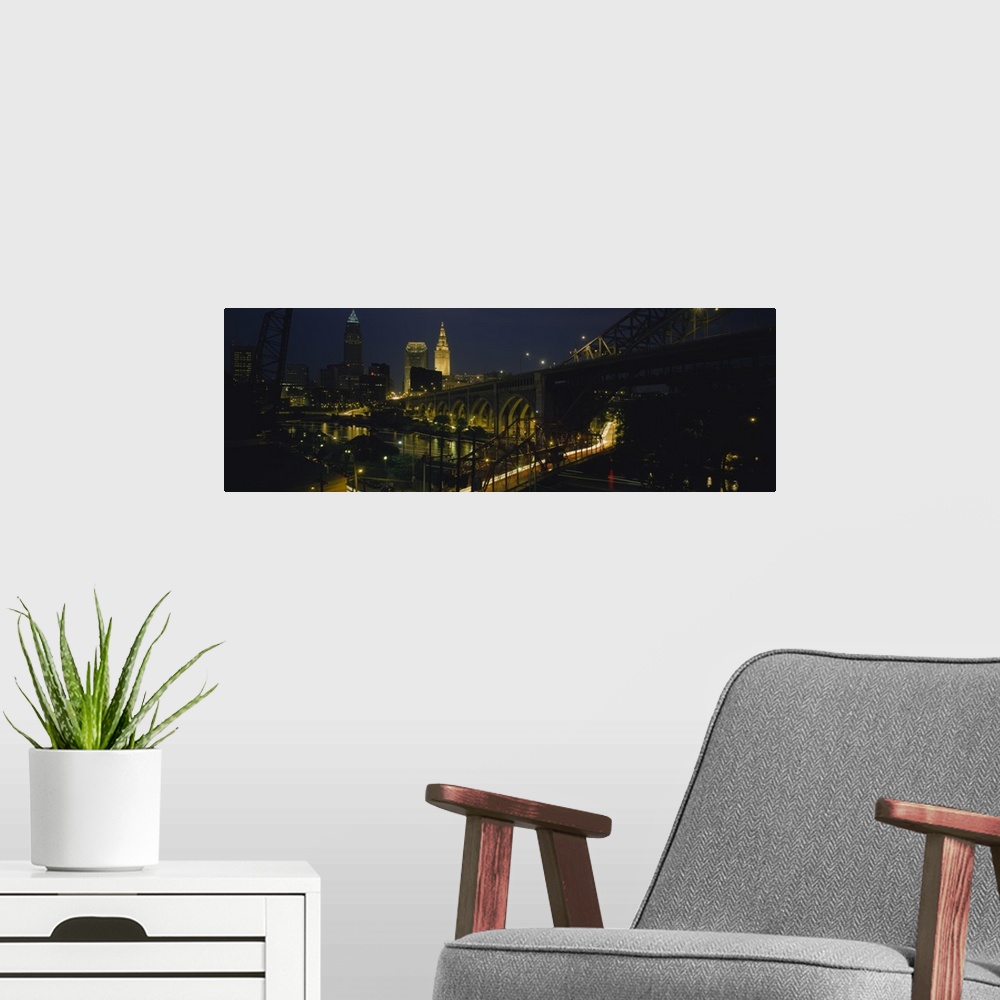 A modern room featuring Lit up downtown buildings and bridges over the Bridge Creek at night in Cleveland, Ohio.