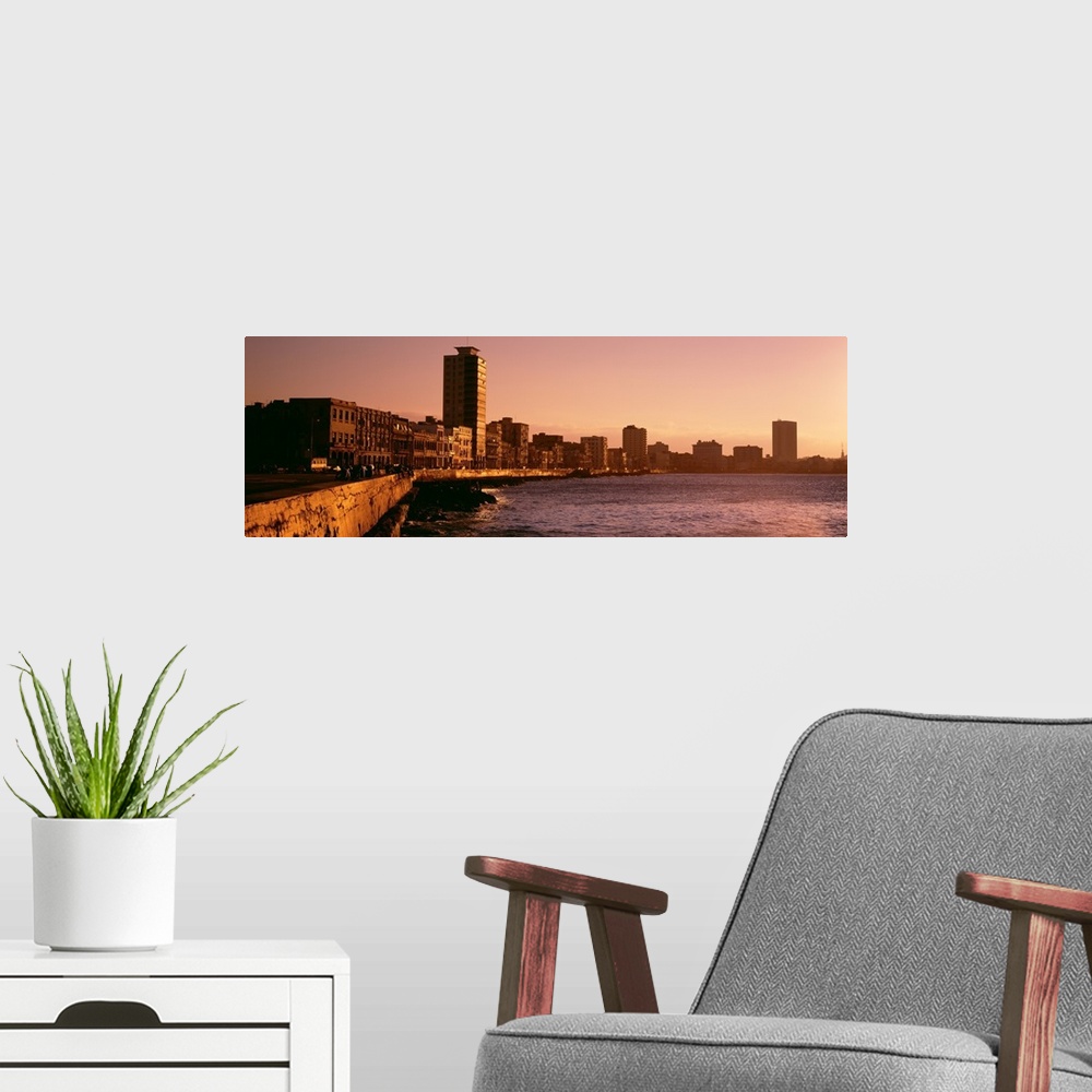 A modern room featuring This wide angle picture is taken of buildings lining a body of water in Havana Cuba during sun down.