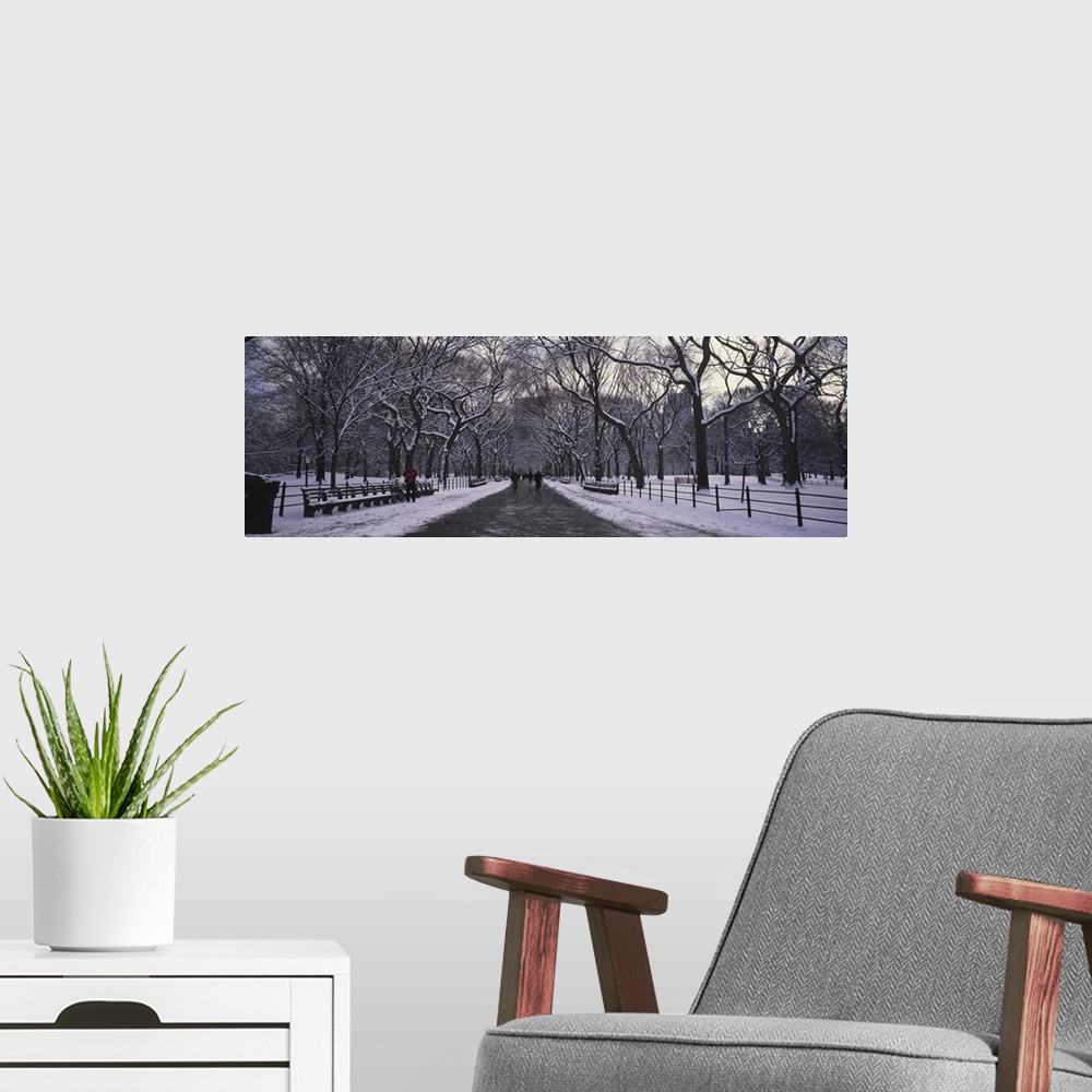 A modern room featuring Panoramic view of a cold, snowy walkway through Manhattan central park in New York.
