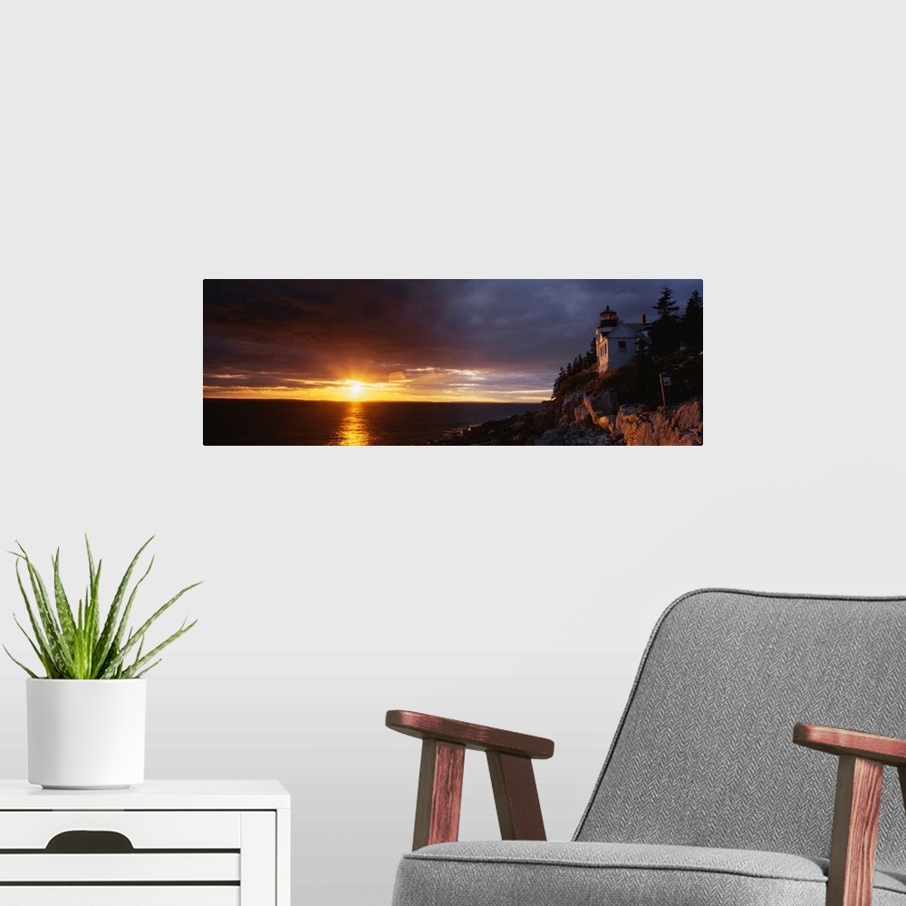 A modern room featuring Large panoramic shot of a sun setting over a harbor with a house on a cliff just to the right.