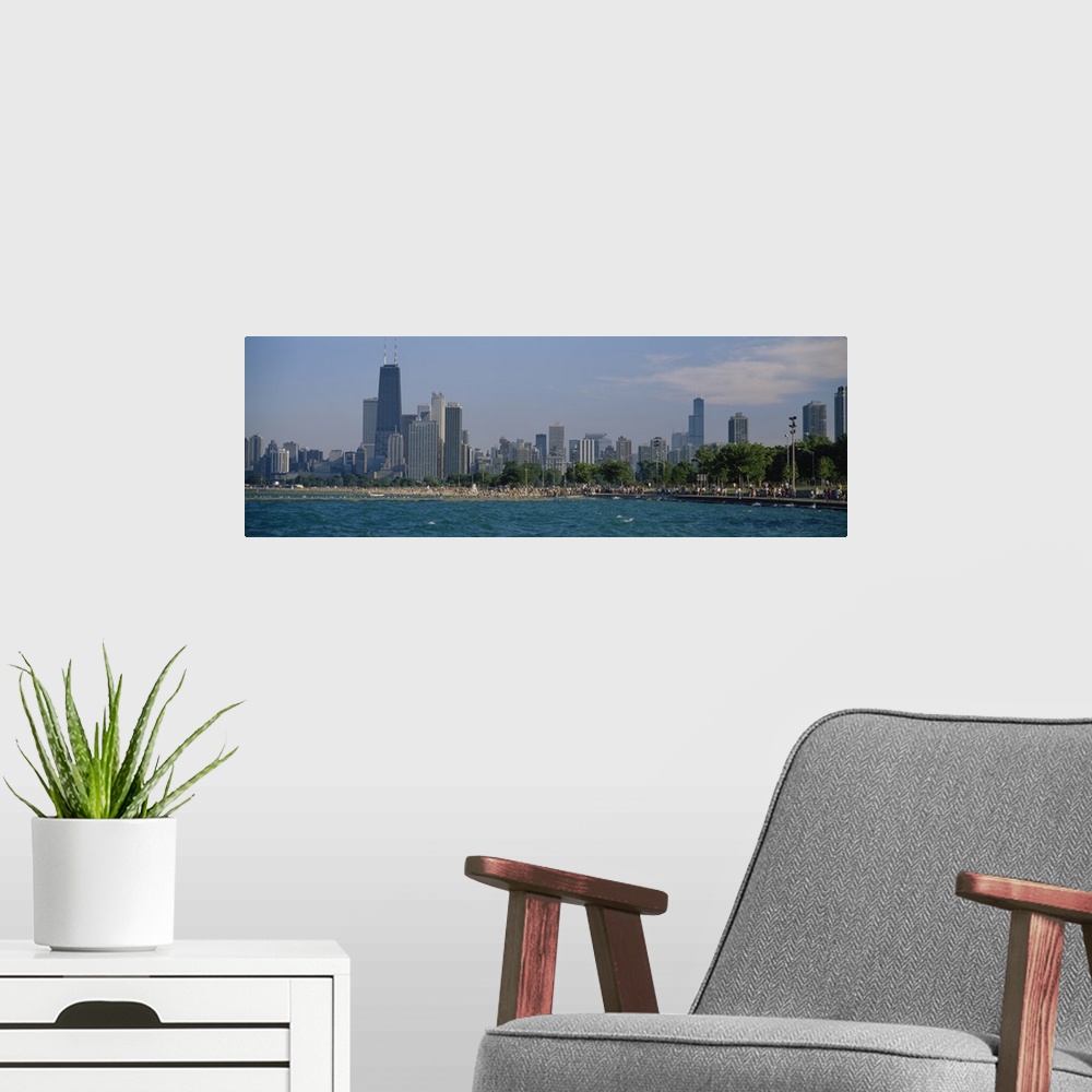 A modern room featuring Oversized, landscape photograph of the Chicago skyline, a crowded beach at the waters edge in the...