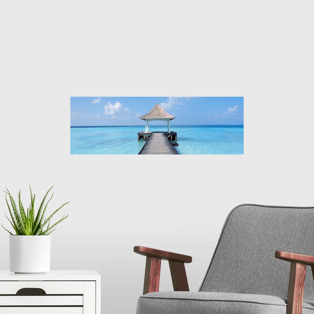 A modern room featuring Oversized panoramic photograph of a pier extending into the crystal clear waters of the Maldives,...