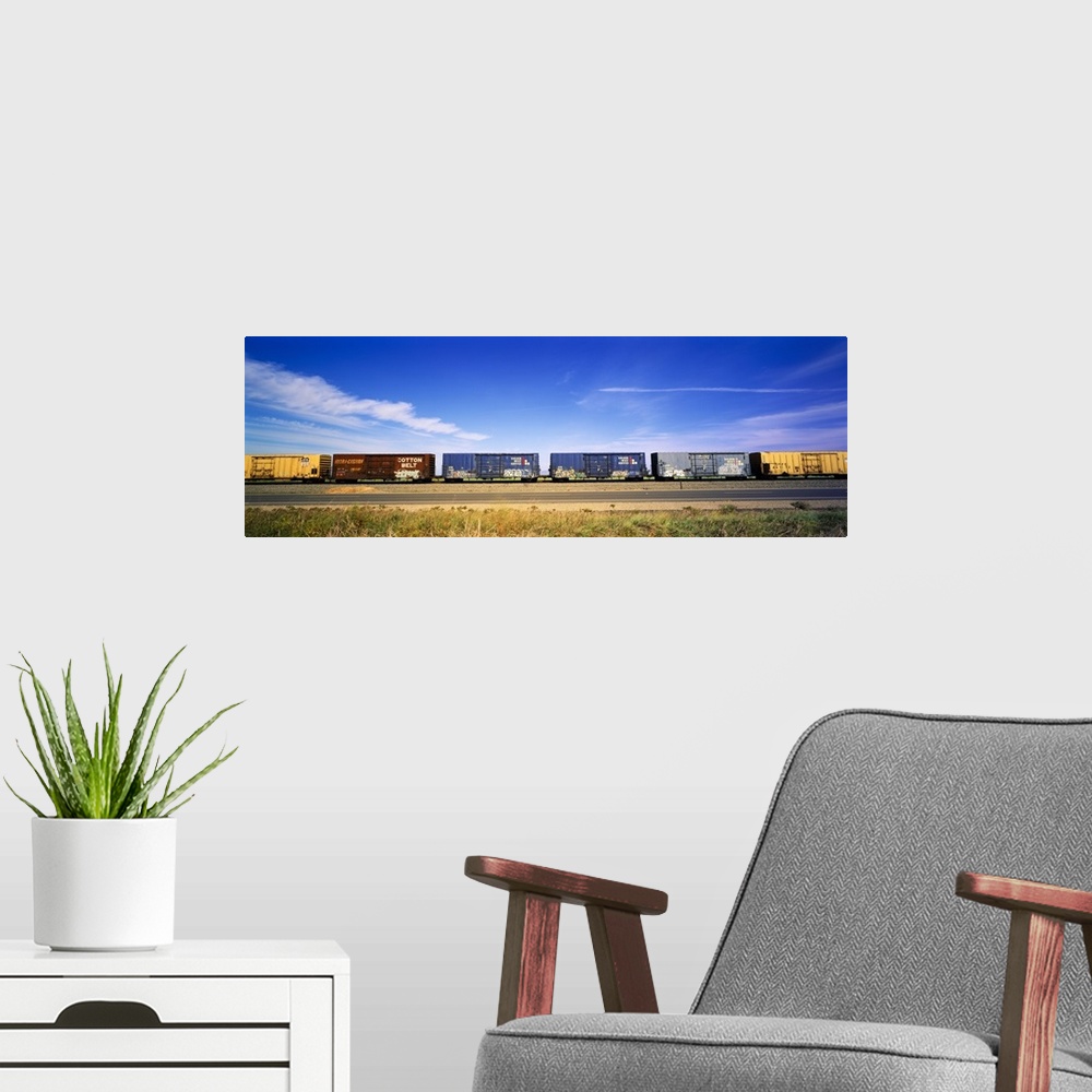 A modern room featuring Panoramic photograph of rusted train cars on a railway under cloudy skies.