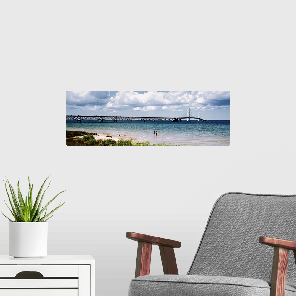 A modern room featuring Panoramic picture of a massive bridge that stretches across a lake in Michigan. Some beach on the...