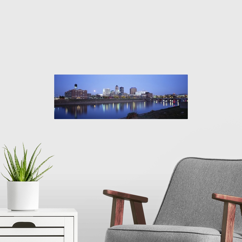 A modern room featuring This panoramic photograph is taken of buildings lit up at night that sit on the water front in De...
