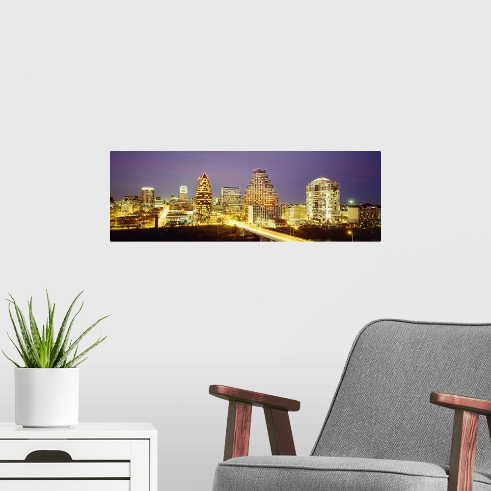 A modern room featuring Panoramic photo of a cityscape brightly lit up at night with slow exposed car lights going throug...