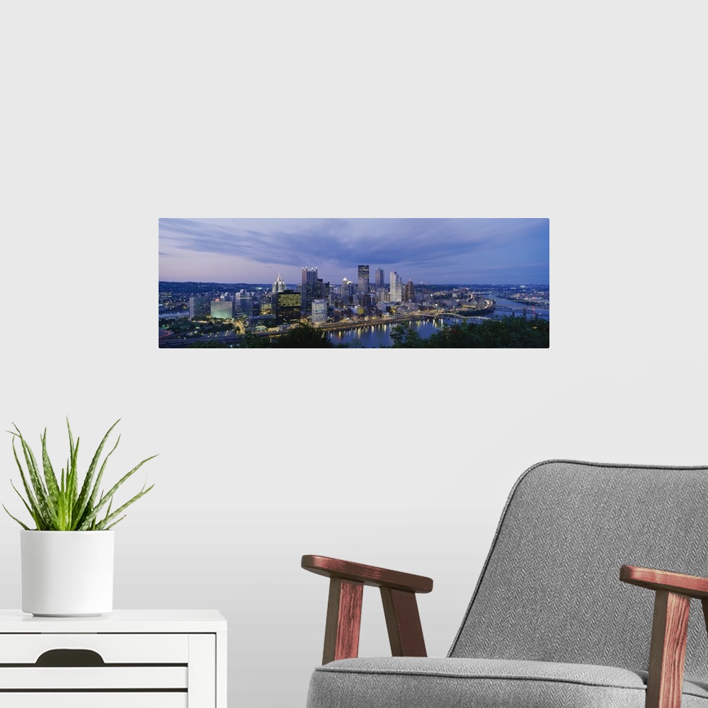 A modern room featuring A beautiful photograph of the Pittsburgh skyline lit up at dusk. The river and trees can be seen ...