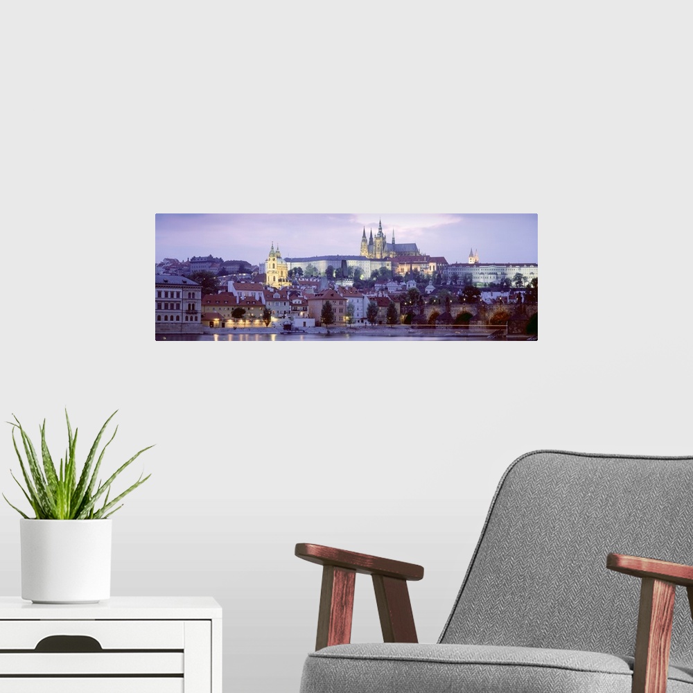 A modern room featuring Wide angle photograph of buildings in Prague, Czech Republic, lit up at night, including Hradcany...