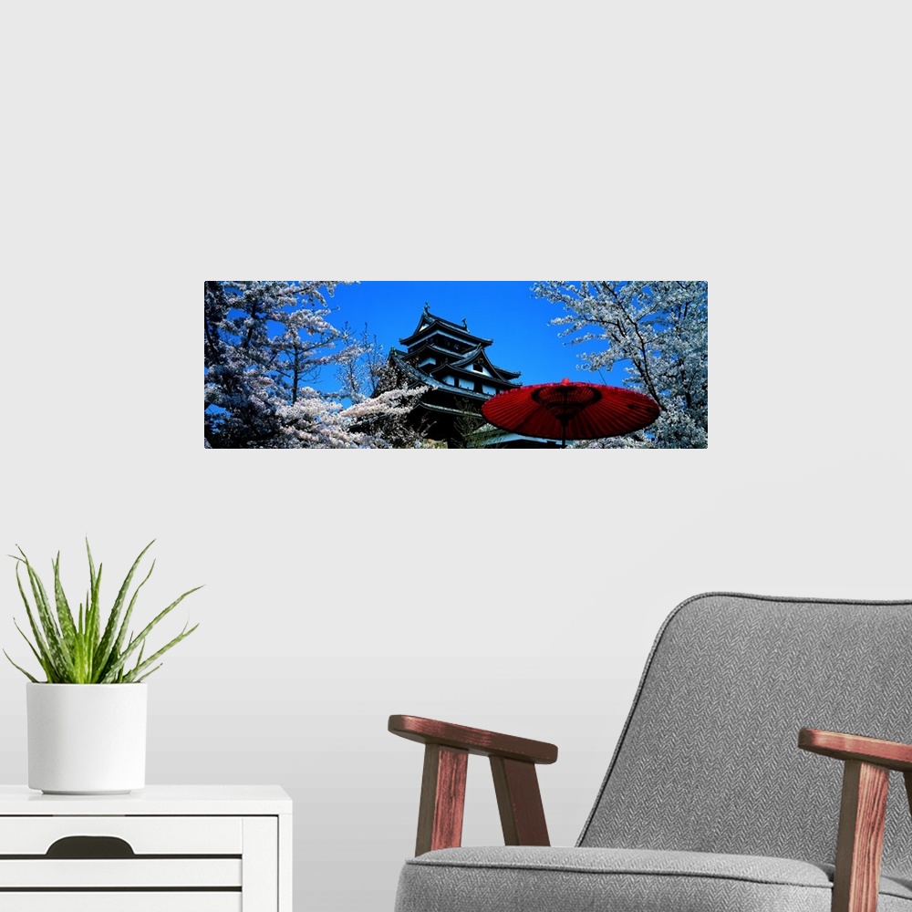 A modern room featuring Beautiful trees are pictured surrounding a Japanese castle with a red umbrella near the bottom ri...