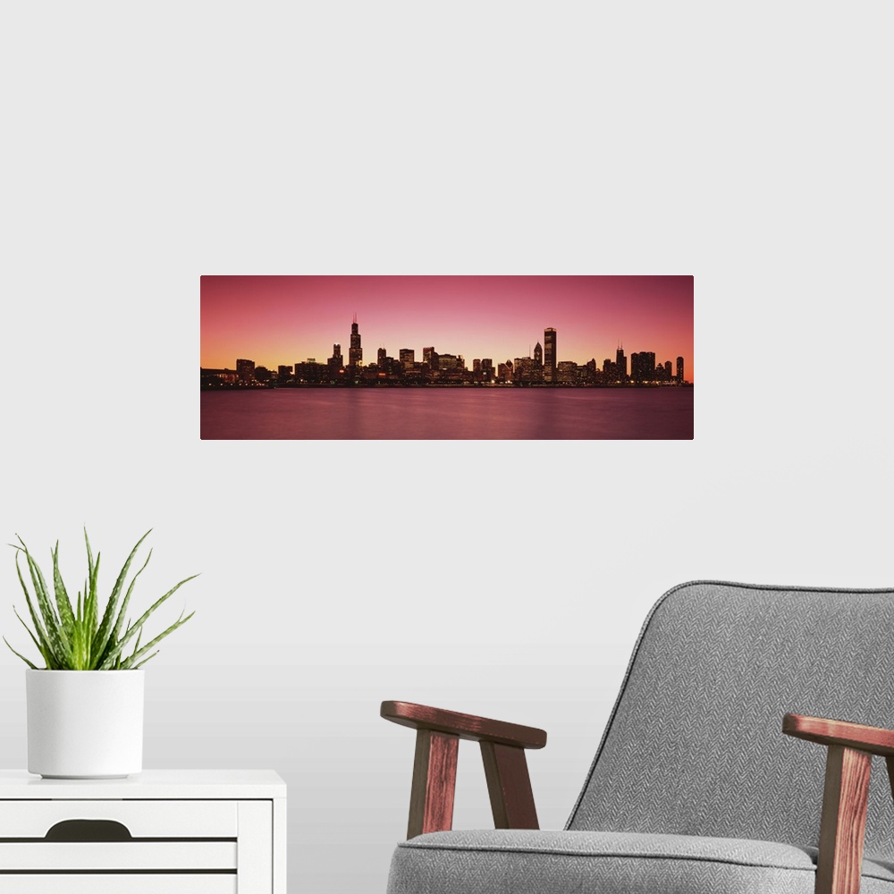 A modern room featuring Panoramic photograph of lit up skyline and waterfront at dusk.