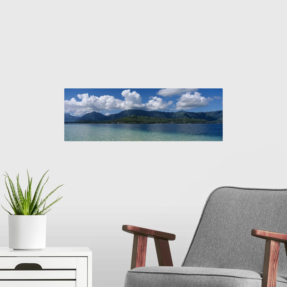 A modern room featuring Panoramic photograph taken across the ocean looking at a Hawaiian island with immense clouds floa...