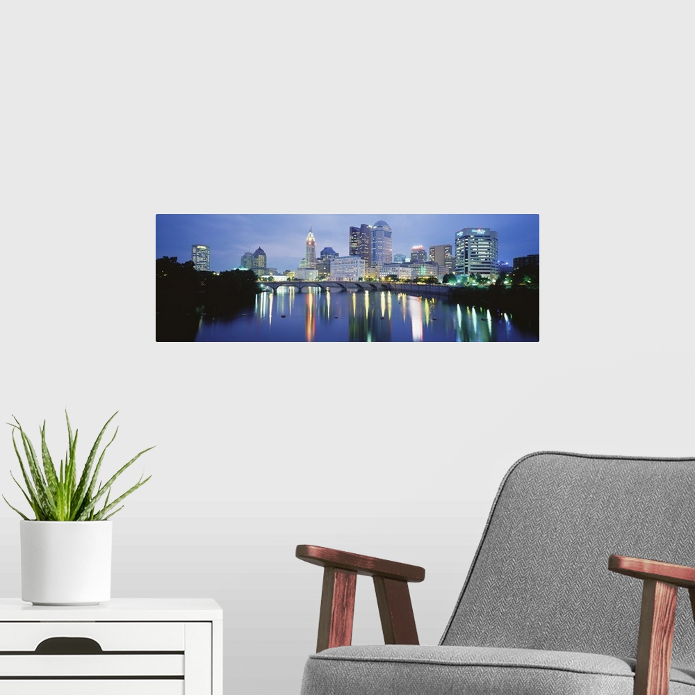 A modern room featuring Giant, horizontal photograph of the Columbus skyline at night, reflecting in the waters of the Sc...