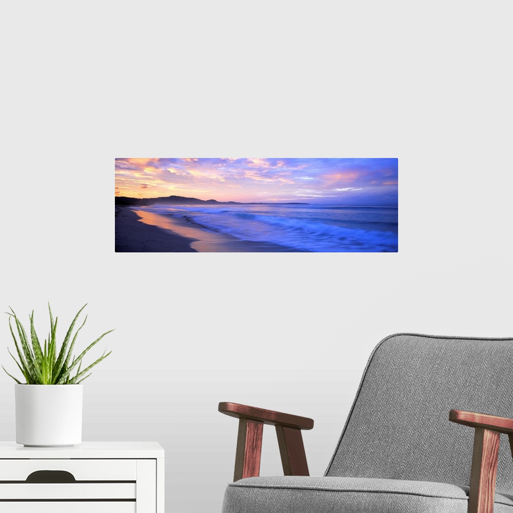 A modern room featuring Panoramic photograph shows waves of an ocean crashing into the bare shoreline of a Central Americ...