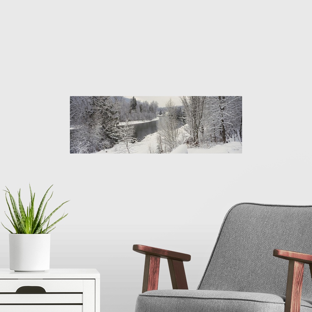 A modern room featuring River and surrounding trees blanketed in snow from a recent snowfall, giving the landscape a quie...
