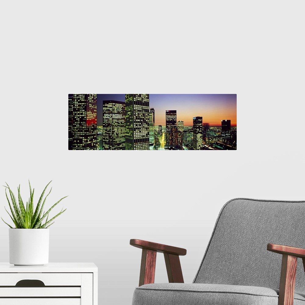 A modern room featuring Panoramic photo of an illuminated cityscape up close to the buildings at sunset.