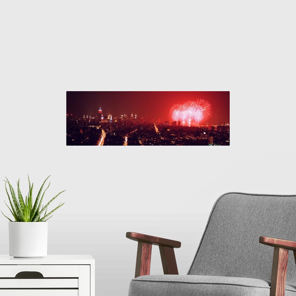 A modern room featuring This glowing panoramic wall art captures the burst of three rockets over the water as well as sev...