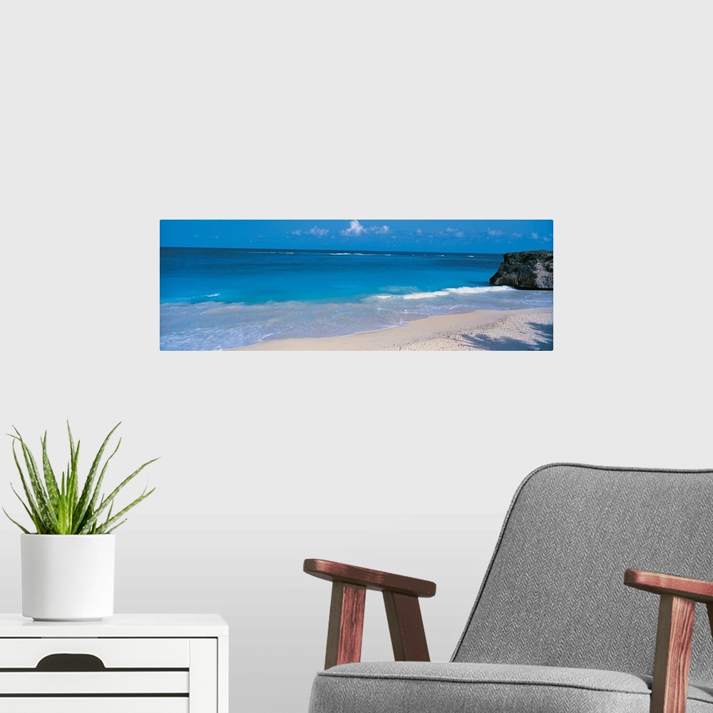 A modern room featuring This is a panoramic photograph of small waves breaking on a sandy tropical beach.