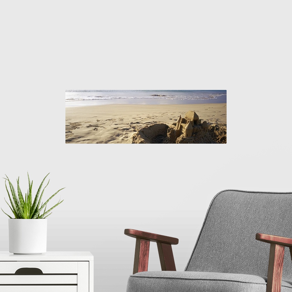 A modern room featuring This landscape photograph of a sandy beach has a elaborate well build castle in the foreground su...