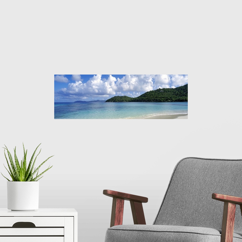 A modern room featuring Panoramic photo on canvas of a clear ocean meeting a shore with rolling hills on the right side.
