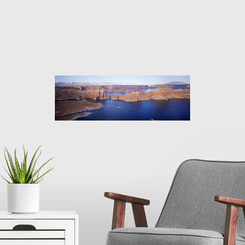 A modern room featuring Panoramic photograph of river running through gorge under a clear sky.