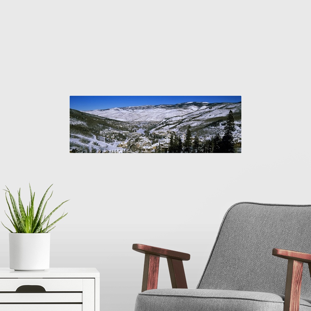 A modern room featuring An aerial photograph taken of ski resort planted in the middle of large mountains covered with sn...