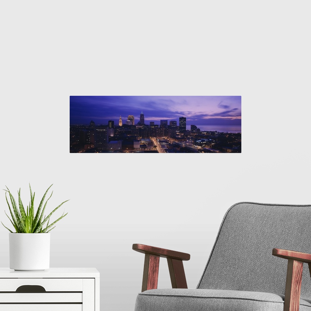 A modern room featuring Panoramic, large photograph from a high angle of the Cleveland skyline, with lit buildings at night.