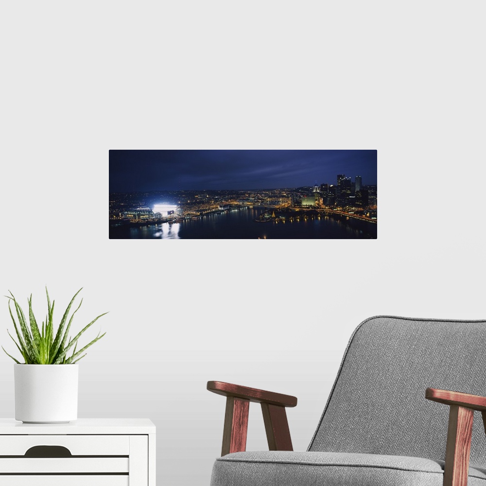 A modern room featuring Panoramic photograph of skyline  and waterfront at dusk with building lights on.