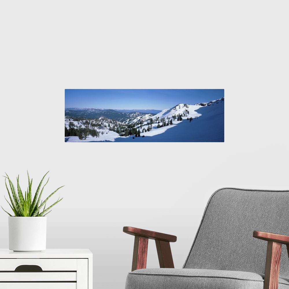 A modern room featuring A panoramic photograph looking down a snow covered mountain into the valley below.
