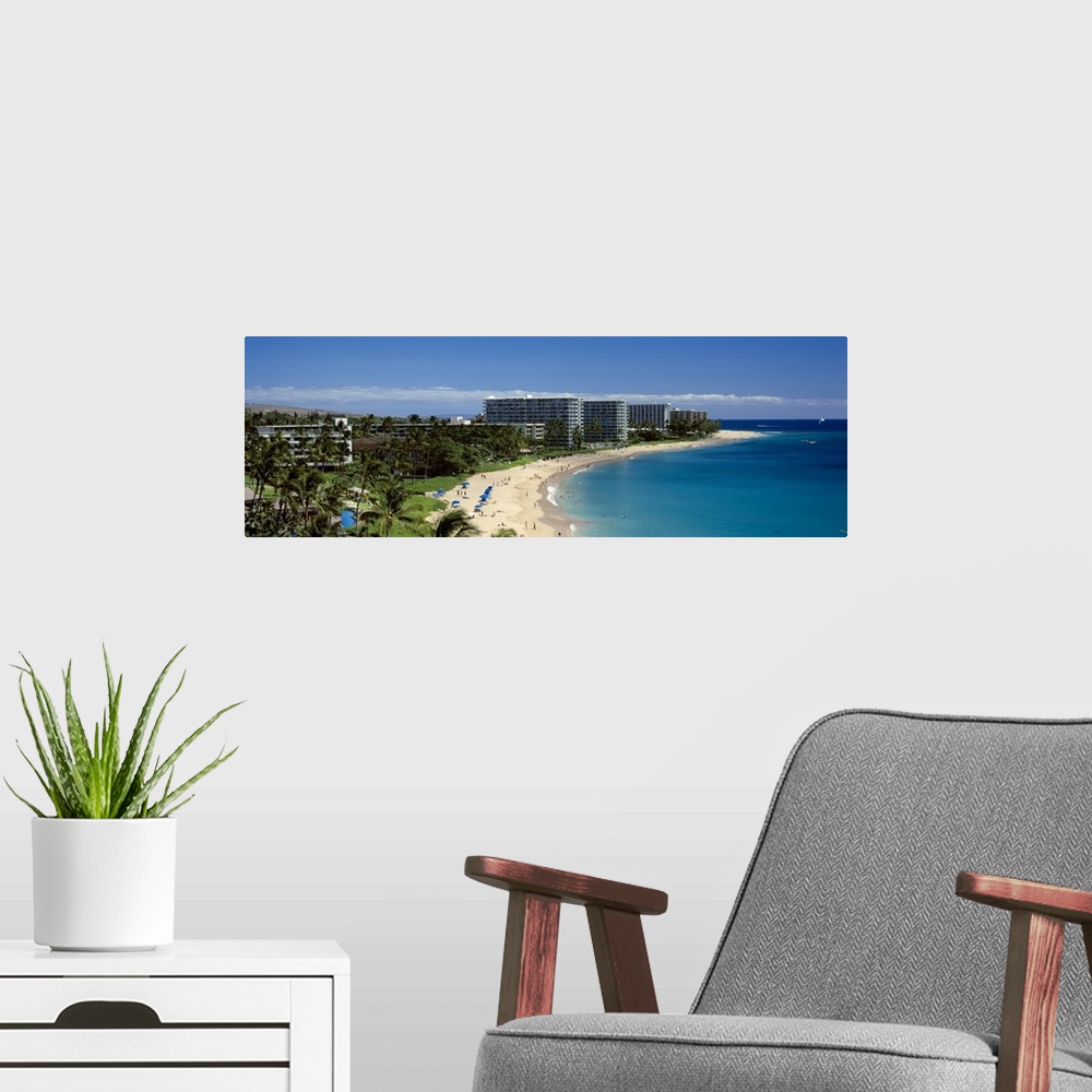 A modern room featuring Panoramic photograph taken of a curved coast in Hawaii that has large hotels lining it.