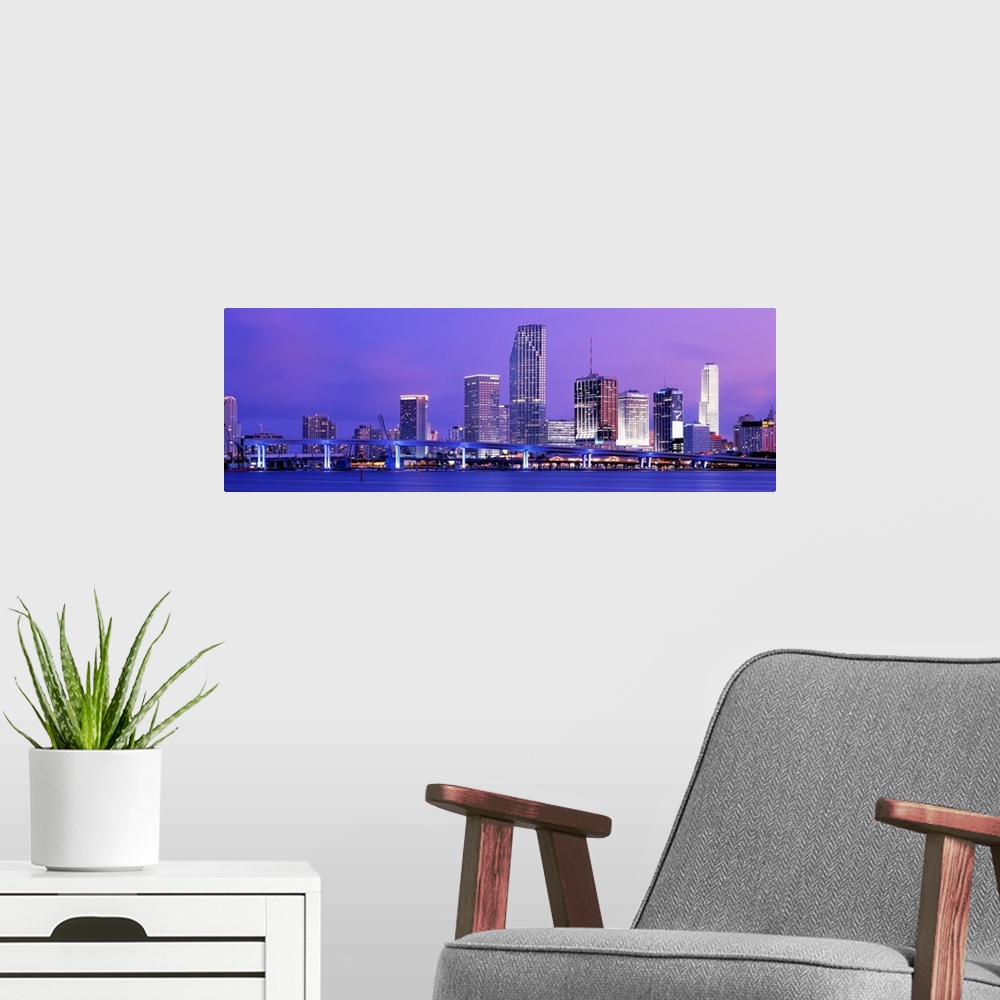 A modern room featuring Wide angle photograph of brightly lit bridge and  skyscrapers of the Miami skyline at sunset.