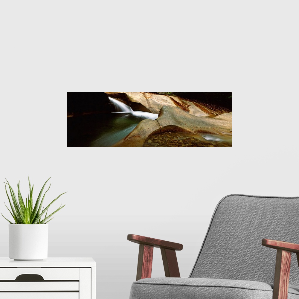 A modern room featuring Horizontal panoramic canvas of water traveling through rocky structures in a cave.