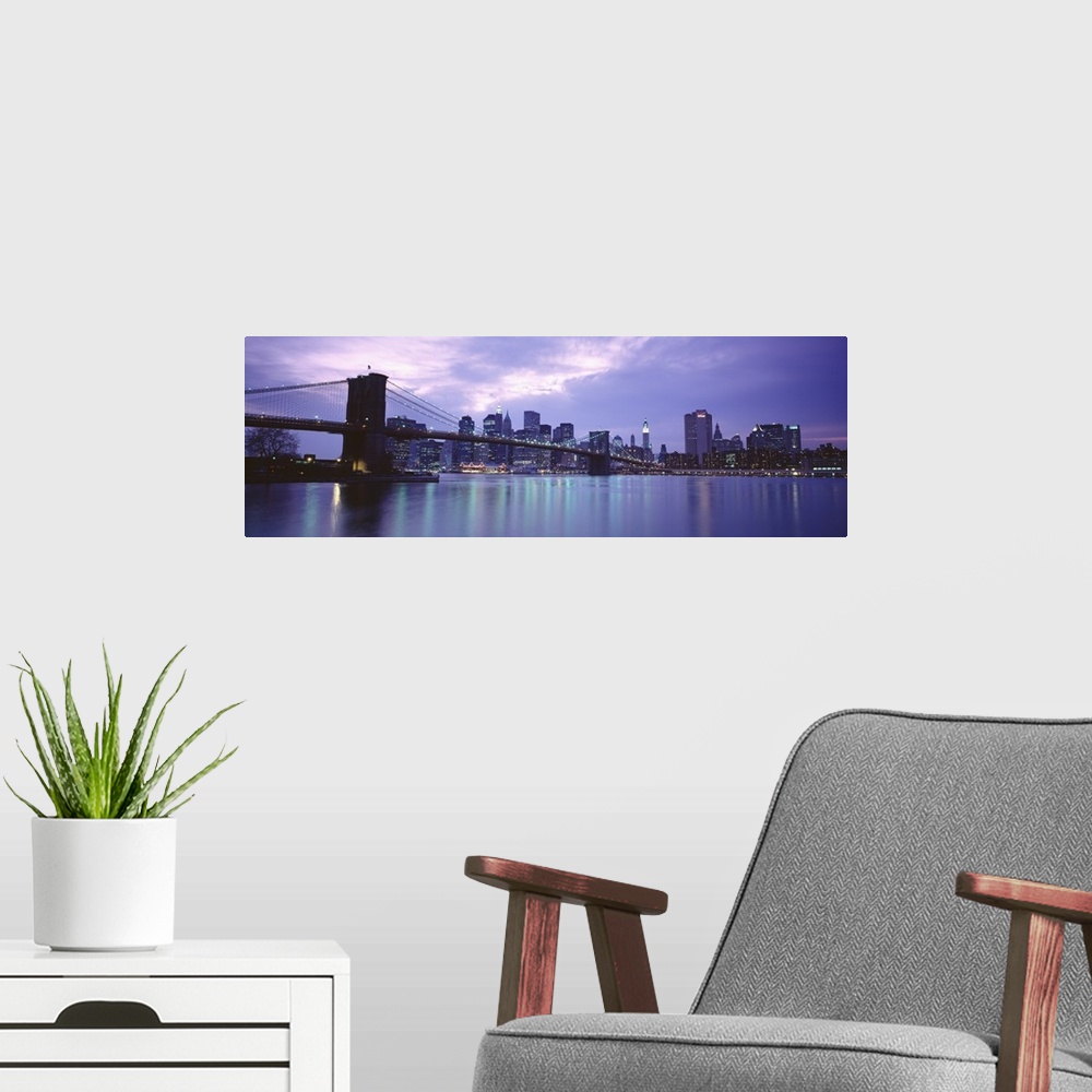 A modern room featuring Large, panoramic photograph of the New York skyline, lit up at night, the Brooklyn Bridge in the ...