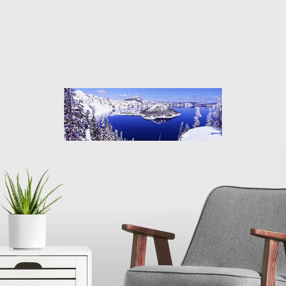 A modern room featuring Wide angle shot taken of Crater lake looking out toward snow covered mountains and pine trees.