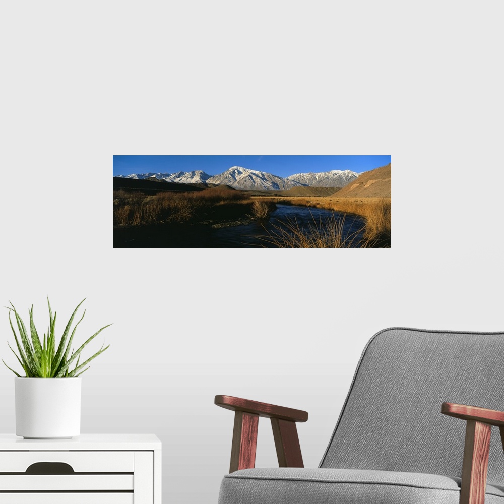 A modern room featuring A mountain range lines the background of this panoramic photograph with a river in the foreground...