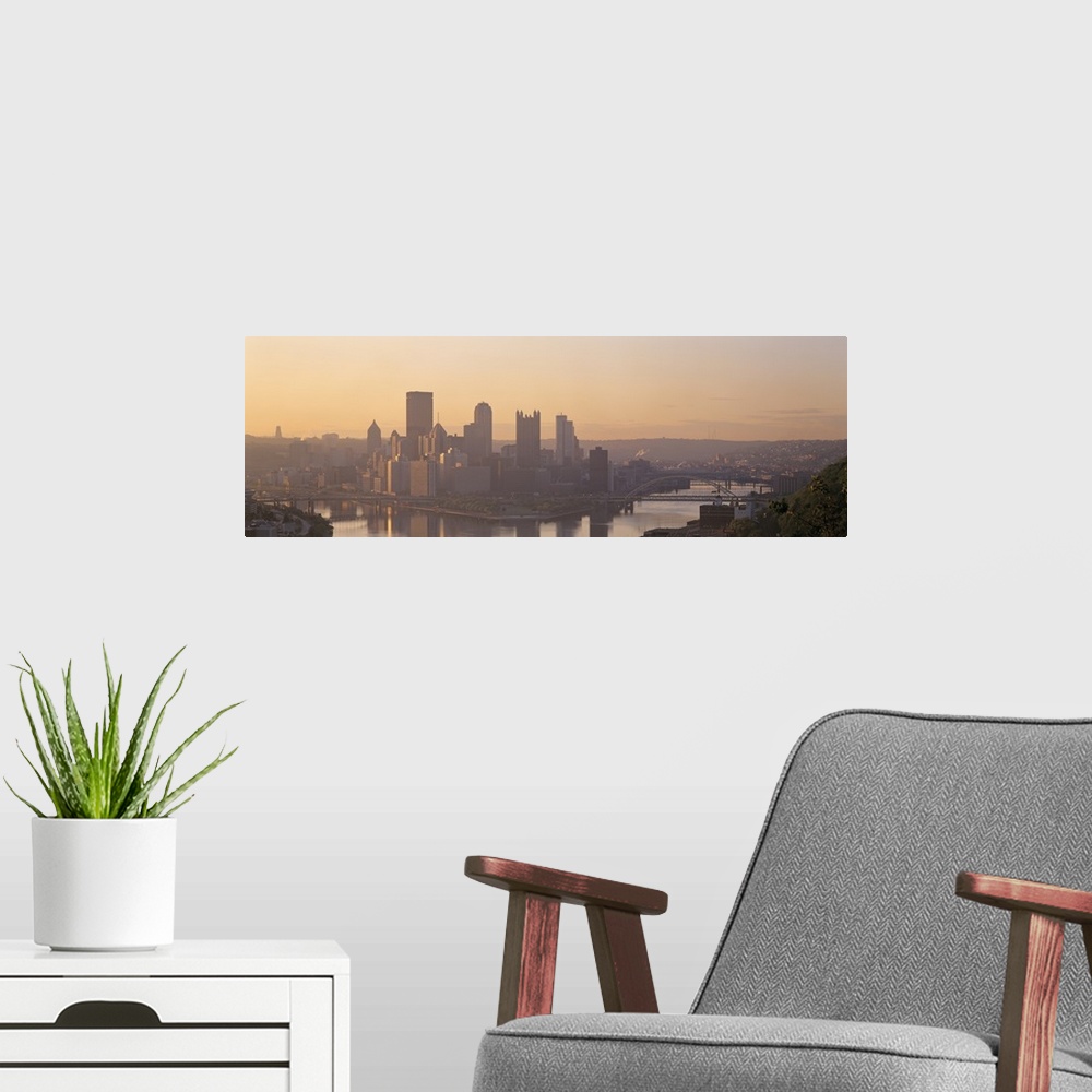 A modern room featuring This is a panoramic photograph of the city skyline between two rivers becoming silhouetted in the...