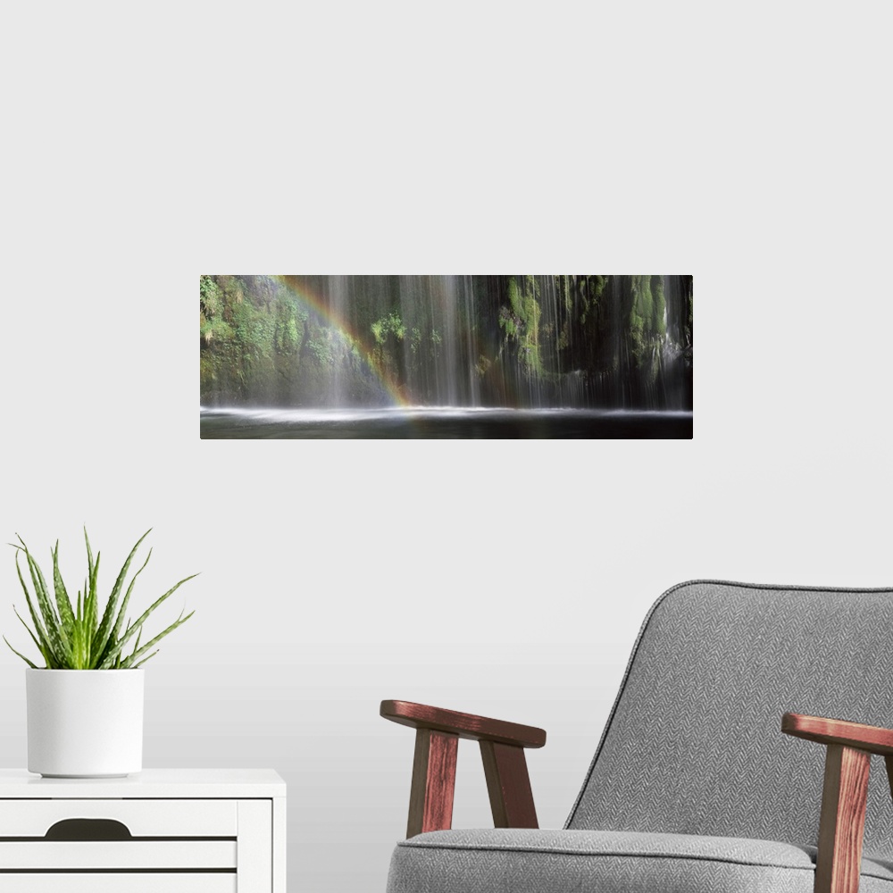 A modern room featuring Panoramic photograph of a double rainbow shown in front of a wide waterfall.