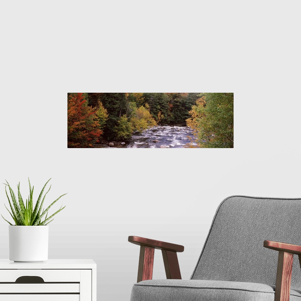 A modern room featuring This decorative landscape wall art is a panoramic photograph of a rock filled river riffling thro...
