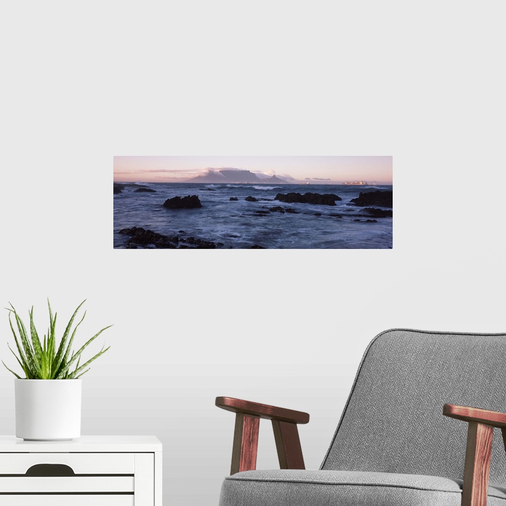 A modern room featuring Rocks in the sea with Table Mountain in the background, Bloubergstrand, Table Mountain, Cape Town...