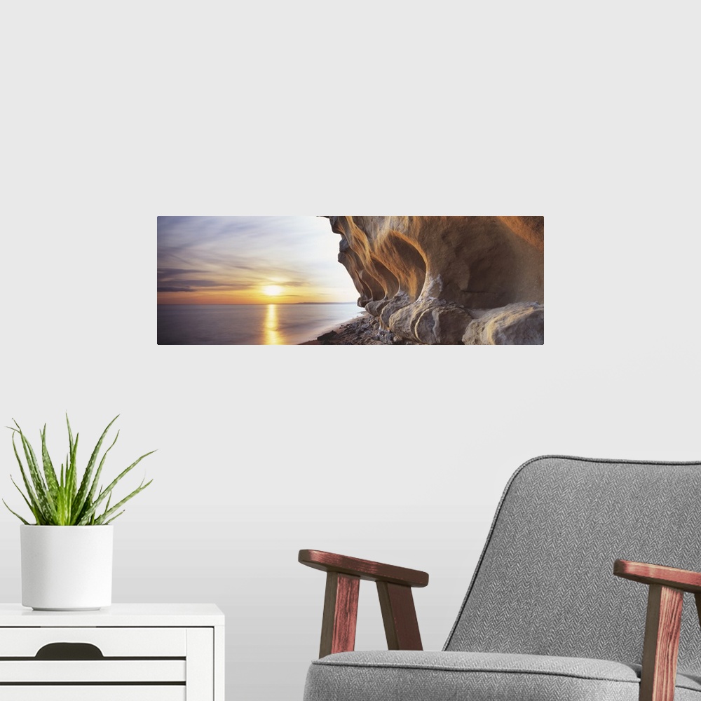 A modern room featuring Eroded rocks by the sea in this panoramic photograph; this is landscape wall art for the office o...